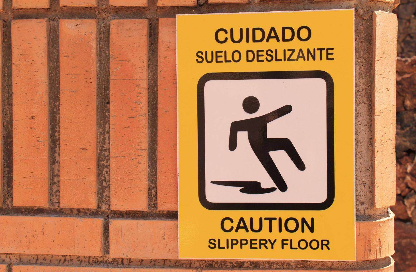 A Slippery Floor sign hung on a brick wall in Alpharetta, Georgia