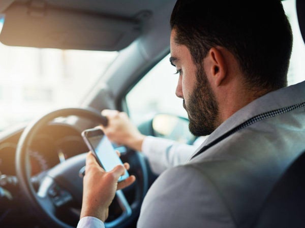 Man-Holding-His-Phone-in-His-Left-Hand-While-Driving